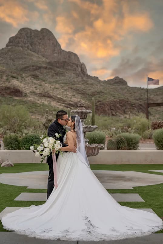 Couple on the ceremony lawn beneath a sunset over Sombrero Peak